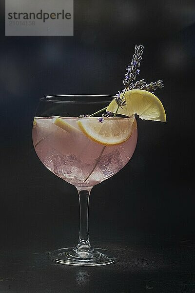 Cocktail with fresh fruit and flowers. Gin and tonic drink with ice at a party  on a black background. Alcohol with lavender and lemon  toned image  Food photography  Food photography