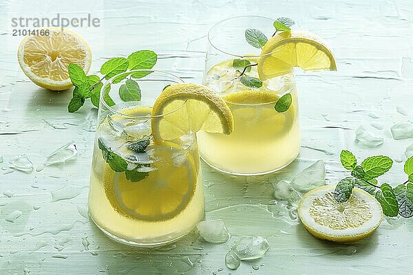 Lemonade with mint. Lemon water drink with ice. Two glasses and lemons on a blue background. Detox beverage. Fresh homemade cocktail  Food photography  Food photography