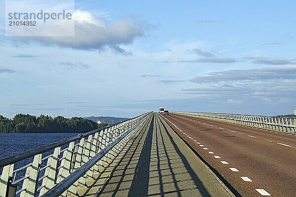 Long bridge over water with blue sky and few clouds  shadow on road  Storsjon  Fröson Bridge  Östersund  Jämtland  Sweden  Europe