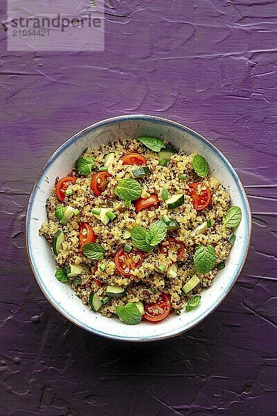 Quinoa tabbouleh salad in a bowl  a healthy dinner with tomatoes and mint  shot from above on a purple background  Food photography  Food photography