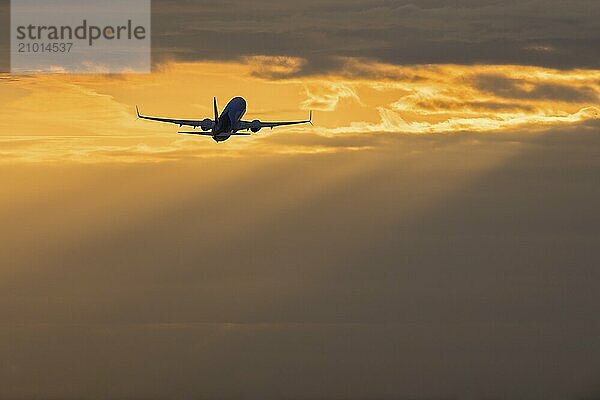 Passenger aeroplane after take-off  clouds  sunbeams  Baden-Württemberg  Germany  Europe