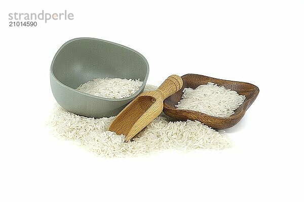 Dry long-grain rice in wooden bowls and wooden scoop isolated on white background