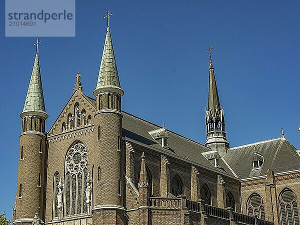 An imposing church with several towers and ornate windows against a clear blue sky  alkmaar  the netherlands