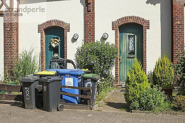 Colourful different dustbins standing in front of a house entrance  Delmenhorst  Lower Saxony  Germany  Europe