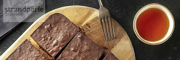 Chocolate brownie with tea panorama  coffee cake panoramic banner  overhead flat lay view on a black background  Food photography