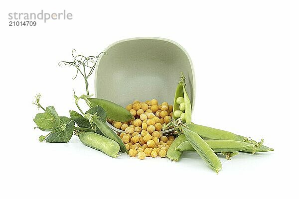 Bowl filled with dried whole yellow peas and fresh garden peas pods with green leaves isolated on a white background