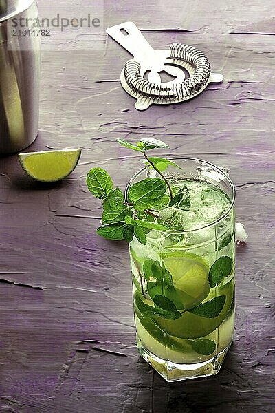 Mojito cocktail. Summer cold drink with lime  fresh mint  and ice. Cool beverage on a purple background  Food photography