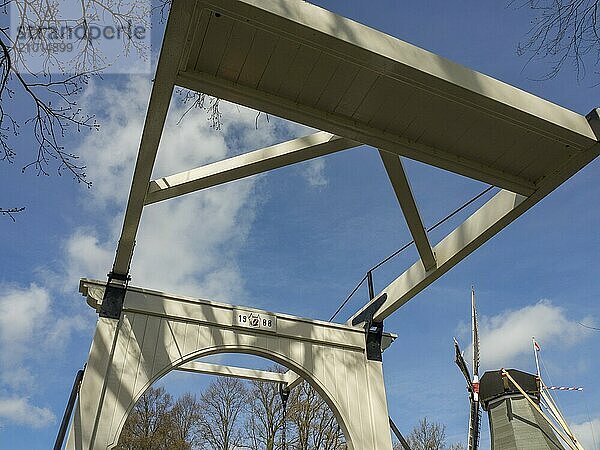 Wooden bridge with blue sky and some clouds in the background  surrounded by trees  Amsterdam  Netherlands