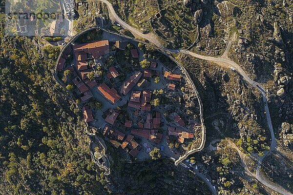 Drone aerialtop above view of Sortelha historic village at sunset with lights on the castle eolic wind turbines and nature landscape  in Portugal