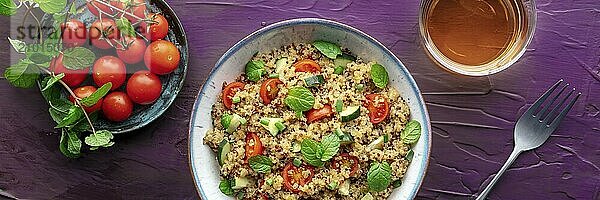 Quinoa tabbouleh salad in a bowl panoramic banner  a healthy dinner with tomatoes and mint  with a drink  overhead flat lay shot on a purple background  Food photography  Food photography