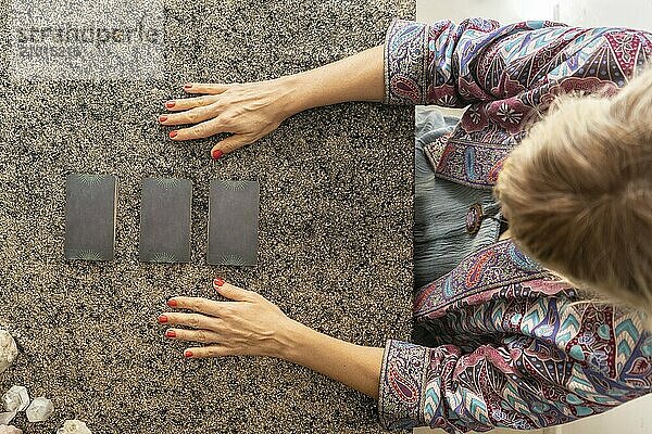 Top view of a tarot reader and three cards turned face down