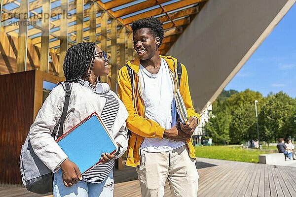 Two casual and happy african american male and female students walking together in the university campus