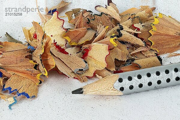 Sharpened black pencil with coloured sharps on a white background