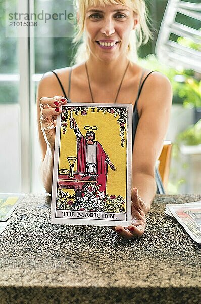 Smiling tarot reader proudly displaying the giant Tarot card The Magician