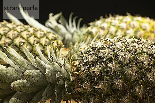 A close up studio photo of a whole pineapple laying on its side against a black background