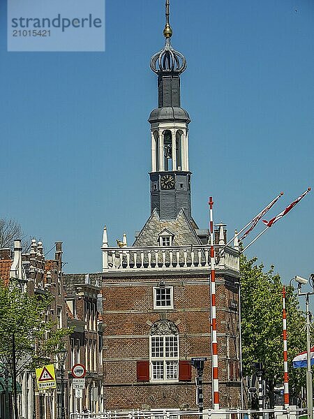 Historic tower with flags on a street under a clear  sunny sky  alkmaar  the netherlands