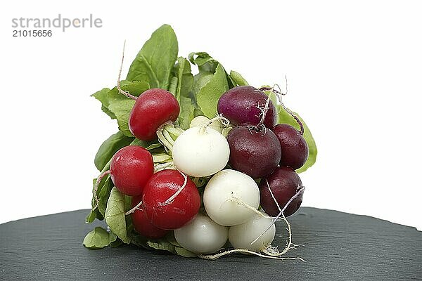 Fresh radish with leaves on black slate serving plate over white background. European radishes (Raphanus sativus)