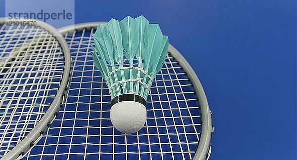 Yellow badminton feather shuttlecock on badminton racket over a blue background  banner size image with copy space