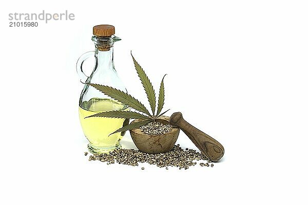 Hemp leaf in front of cannabis oil in glass decanter and hemp seeds isolated on white background. Benefits and uses of hemp (Cannabis sativa)