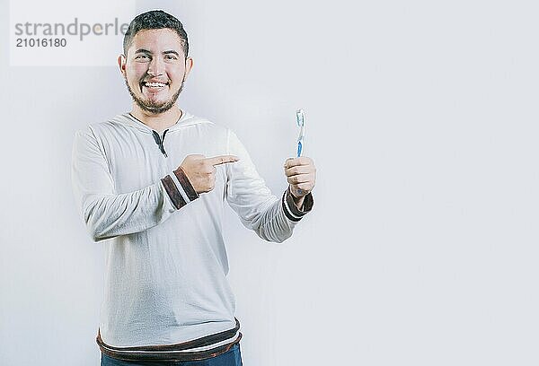 Happy guy pointing at toothbrush isolated. Handsome man holding and pointing toothbrush isolated