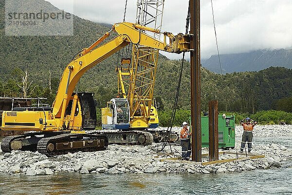 Builders drive pylons for a concrete bridge over a small river in Westland  New Zealand  Oceania