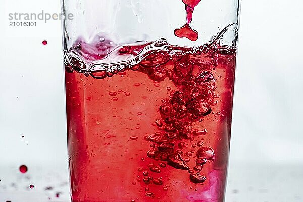 Red liquid being poured into a glass. White background