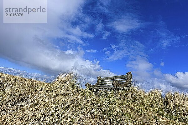 A park bench under a partly cloudy sky on Del Ray beach in Seaside  Oregon