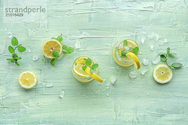 Lemonade with mint. Lemon water drink with ice. Two glasses and lemons on a blue background  overhead flat lay shot with copy space. Detox beverage. Fresh homemade cocktail  Food photography