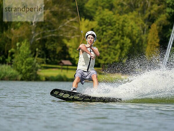 Young man on wakeboard in splashing water  cheerful  water skiing and wakepark  water sports