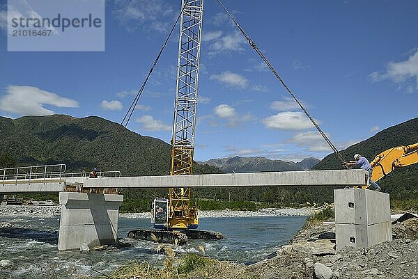 Builders construct a concrete bridge over a small river in Westland  New Zealand  Oceania