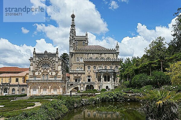 Ein prächtiges Schloss mit aufwendiger Architektur und Türmen vor einem blauen Himmel mit Wolken  umgeben von einem gepflegten Garten mit Teichen  Palácio Hotel do Buçaco  Mata Nacional do Buçaco  National-Wald von Bussaco  Bucaco  Mealhada  Beira Litoral  Portugal  Europe