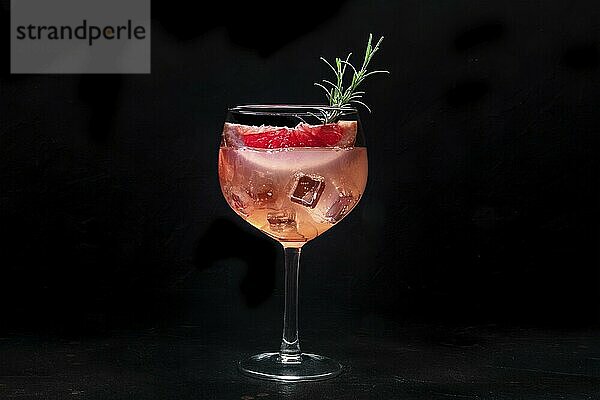 Fancy cocktail with fresh fruit. Gin and tonic drink with ice at a party  on a black background. Alcohol with pink grapefuit and rosemary  Food photography