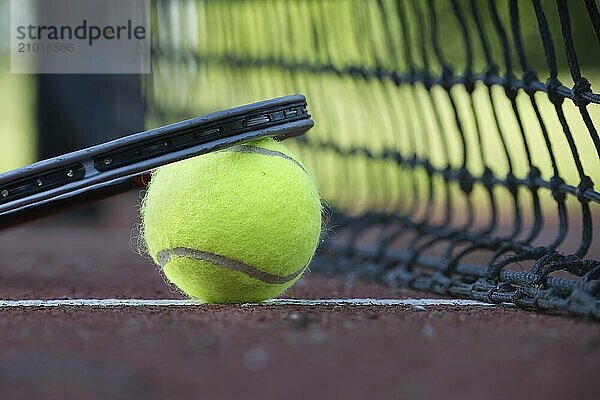 Tennis scene with black net  ball on white line and racquet in low angle view