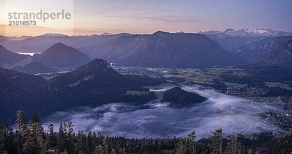 View from Mount Loser to Lake Altaussee  Altaussee  Bad Aussee  Tressenstein  Zinken  Dachstein mountains. Wisps of mist over the lake. In the morning in front of sunrise. Blue sky. Autumn. Altaussee  Bad Aussee  Ausseer Land  Totes Gebirge  Styria  Upper Austria  Austria  Europe