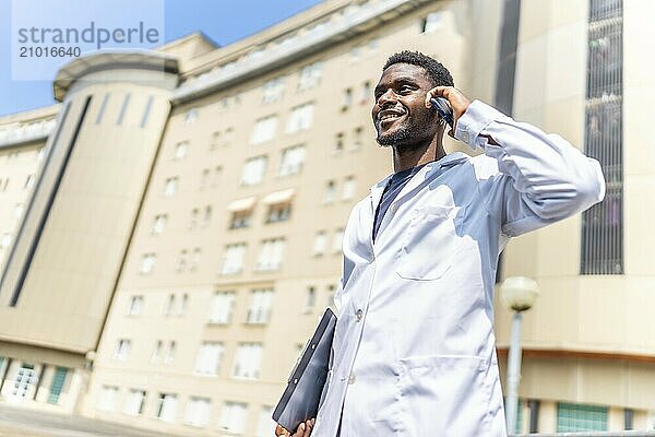 Low angle view portrait of a confident young african doctor talking to the mobile outside the hospital