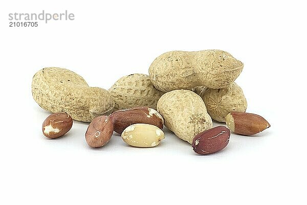 Pile of shelled and unshelled dried peanuts scattered on white background