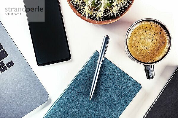 Desk  top view on a white background. Coffee  notebook and pen  phone  plant  and laptop  overhead flat lay shot  Food photography