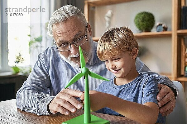 Grandpa helps his grandson play with a wind turbine  AI generated  AI generated