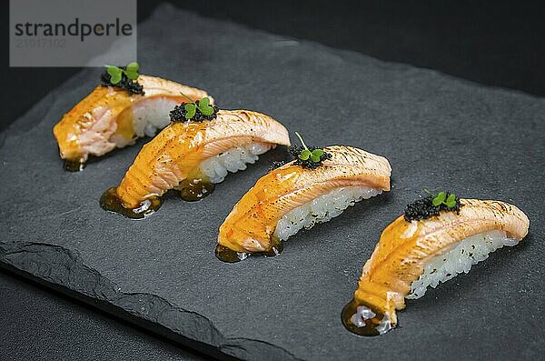 Perfect sushi  traditional Japanese cuisine. Delicious salmon kiguiri with capellin roe (caviar) on the decorated plate  black background