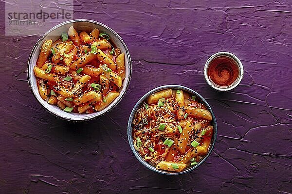 Tteokbokki or topokki and rabokki  Korean street food  spicy rice cakes  overhead flat lay shot with a drink on a purple background  Food photography  Food photography