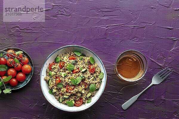 Quinoa tabbouleh salad in a bowl  a healthy dinner with tomatoes and mint on a purple background  overhead flat lay shot with a place for text  Food photography  Food photography