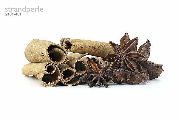 Pile natural cinnamon sticks and anise stars with a seed inside isolated on white background