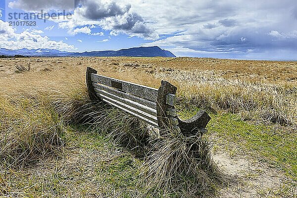 A park bench under a partly cloudy sky on Del Ray beach in Seaside  Oregon