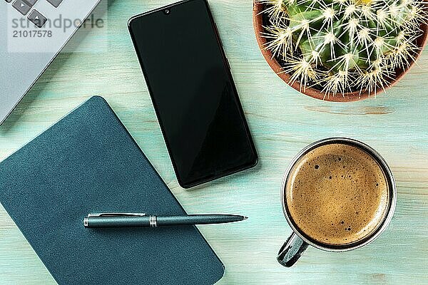 Desk  top view on a wooden blue background. Coffee  notebook and pen  phone  plant  and laptop  overhead flat lay shot. Work layout  Food photography