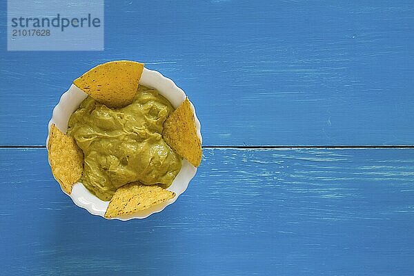 Salsa guacamole and nachos chips over a blue background seen from above