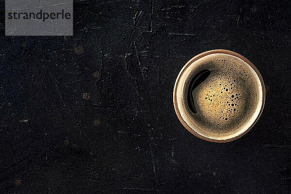 A cup of black coffee with froth  overhead flat lay shot on a black background  with copy space  Food photography  Food photography