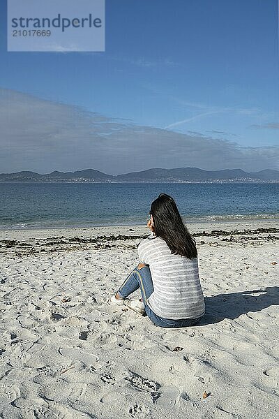 Woman sit and relaxing on the white sand of Oia beach in Galicia  Spain  Europe