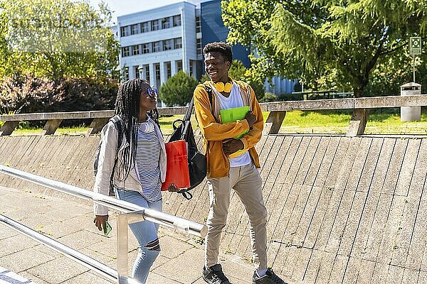 Side view full length of two African american students strolling and talking along the campus