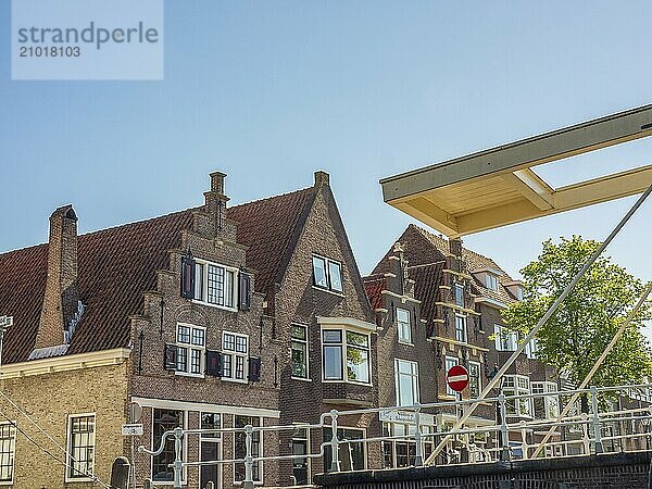 Row of historic brick buildings along a canal  next to a bridge under a clear sky  alkmaar  the netherlands