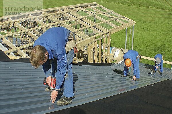 Builders working on the roof of a large house